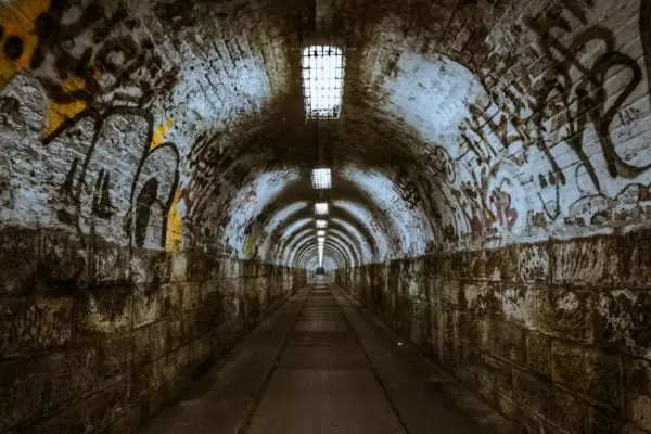 Długi tunel pokryty graffiti. Na końcu nie widać wyjścia