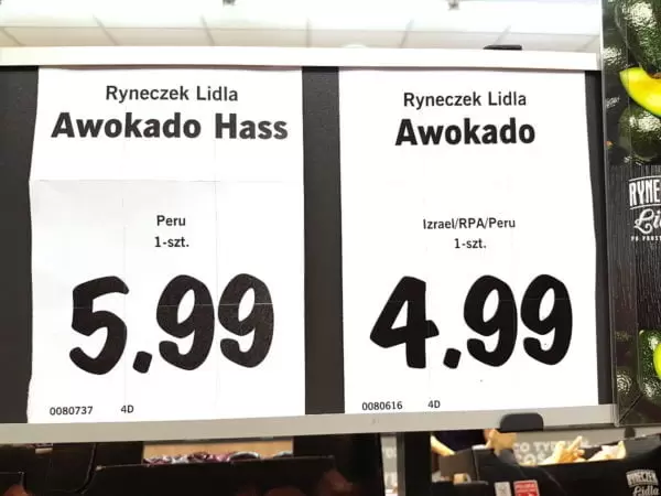 Sklepowe etykiety z nazwą produktów, ceną i krajem pochodzenia. Na jednej z nich czytamy: „Awokado. Izrael/RPA/Peru. 1-szt. 4,99”.